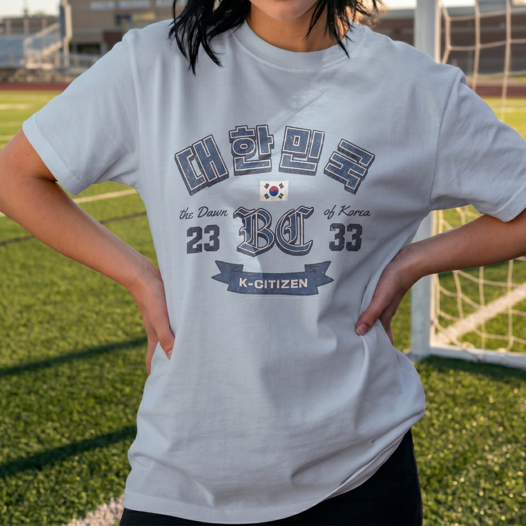lifestyle shot of a woman, wearing a light blue t-shirt with a vintage "대한민국" (Daehanminguk) Hangul K-citizen t-shirt