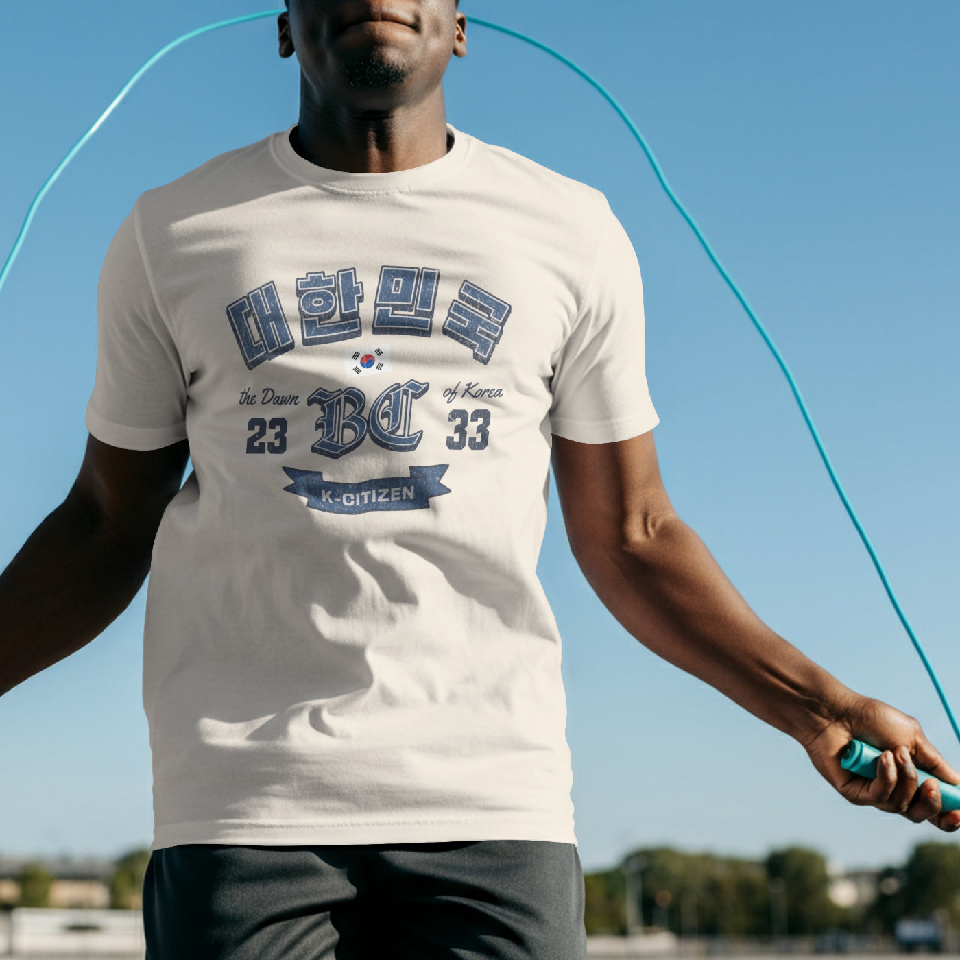 A man exercise wearing an off-white graphic t-shirt featuring a vintage Korean heritage design. The shirt displays the Korean text "대한민국" (Republic of Korea) in a distressed blue font