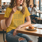Lifestyle shot of a woman in a mustard yellow K-citizen t-shirt holding a coffee cup with Seoul Soul graphic