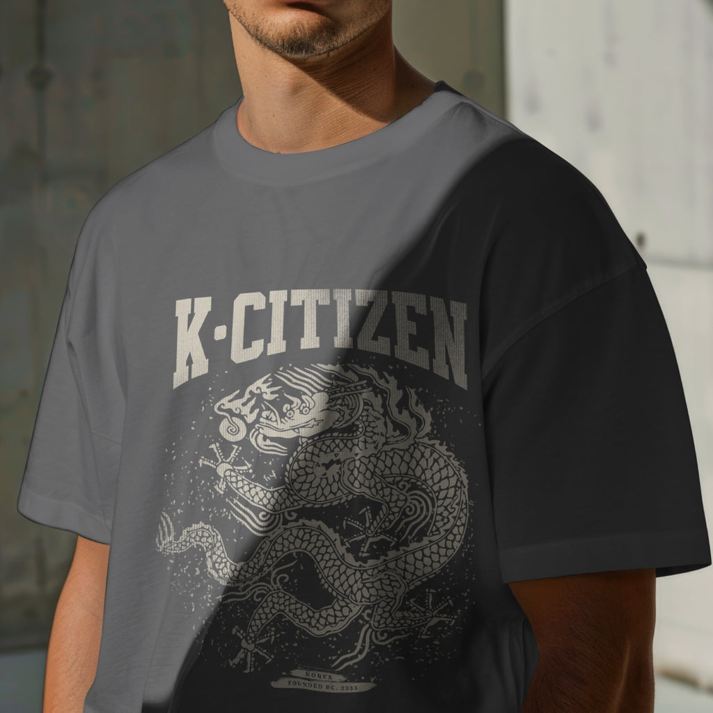 Person wearing a gray t-shirt with 'K-Citizen' and dragon design.