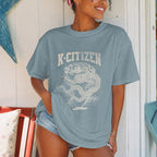Person wearing a blue t-shirt with 'K-Citizen' and korean royal dragon design in summer cottage background