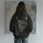 Person wearing a black hoodie with a dragon design in front of a painting