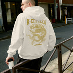 Person wearing a white hoodie with a dragon design and 'K-City' text, walking on a street.